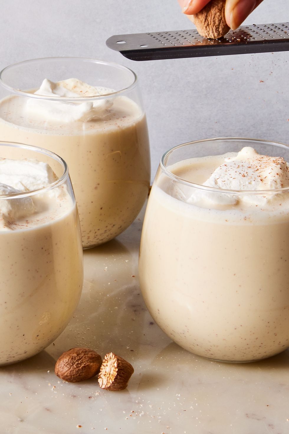 homemade eggnog topped with whipped cream and grated nutmeg