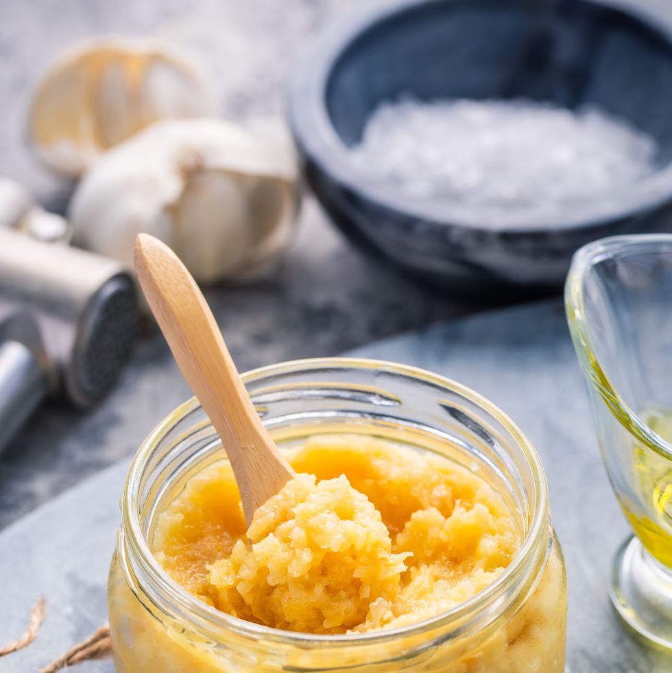 homemade garlic paste in a jar with peeled garlic, salt, crusher and garlic heads.