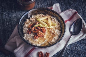 kom vol havermout met pecannoten en fruit, doekje en lepel ernaast