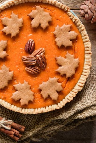 Homemade pumpkin pies with pecan nuts and gingerbread cookies decoration on old wooden table