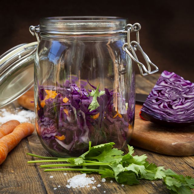 homemade red cabbage, fermented, with chili, carrot and coriander, preserving jar on wood