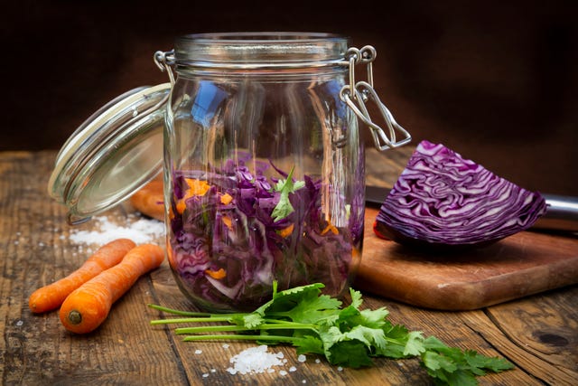 homemade red cabbage, fermented, with chili, carrot and coriander, preserving jar on wood