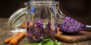 homemade red cabbage, fermented, with chili, carrot and coriander, preserving jar on wood