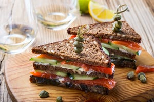 homemade salmon club sandwich on rye bread with cucumber and sauteed spinach and secure with cocktail sticks