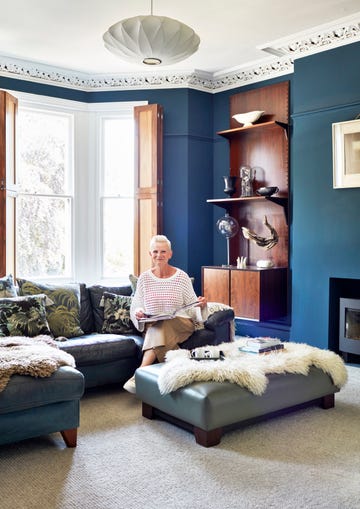 blue living room with grey leather sofas covered in botanical cushions