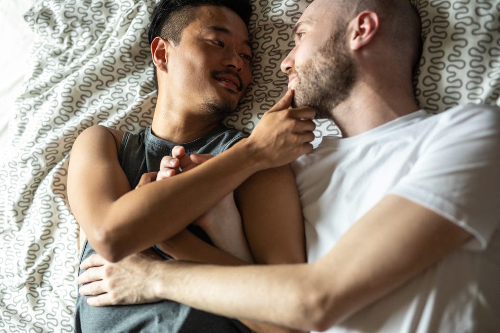 homosexual couple lying and cuddling in bed