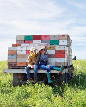 a couple of kids sitting on a truck with a large load of garbage