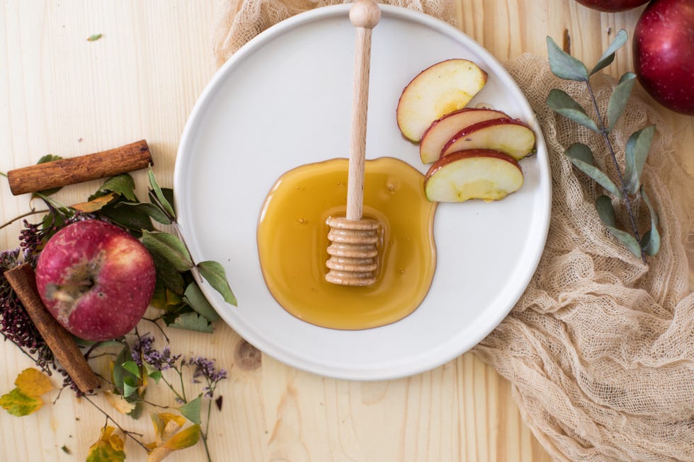 honey dipper and apple slices in plate on table