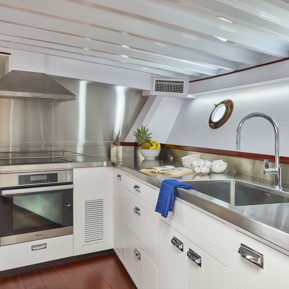 a small kitchen with white cabinets, metal countertops inside the honey fitz yacht