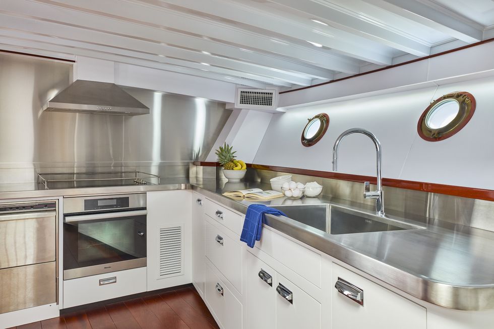 a small kitchen with white cabinets, metal countertops inside the honey fitz yacht