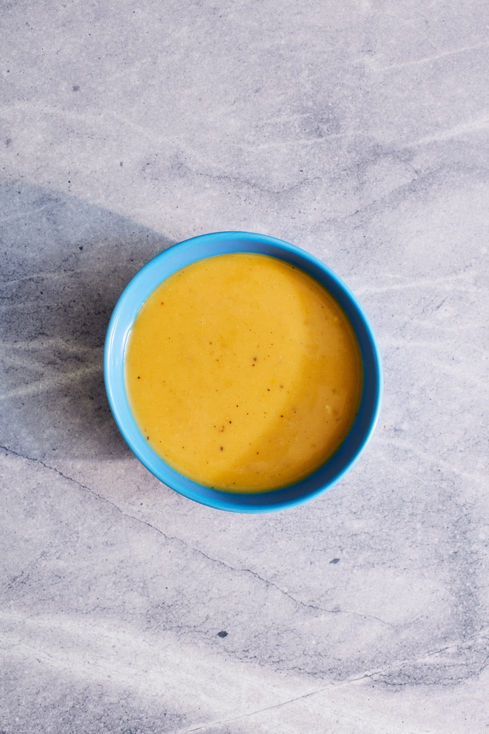 honey mustard dressing in a blue bowl on a marble background