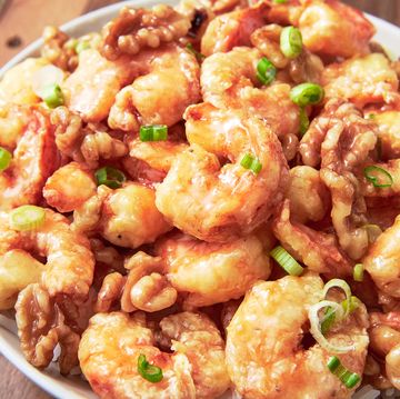 closeup of honey walnut shrimp garnished with scallions in a white bowl