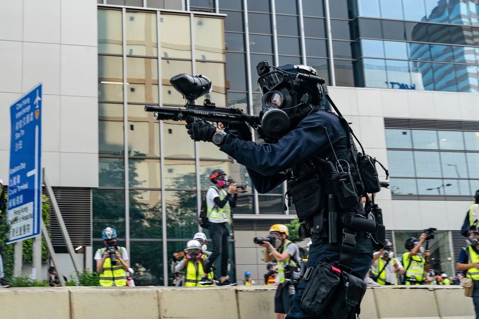 a riot police officer fires rubber bullets at protesters during an anti government rally in kowloon bay district, hong kong, on 24 august 24, 2019
