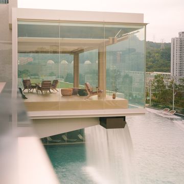 da un edificio di vetro in aggetto scorre una fontana che si getta in una piscina