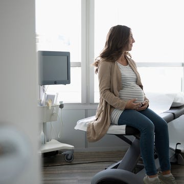 Hopeful pregnant woman waiting in clinic examination room