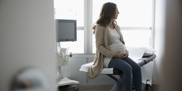 Hopeful pregnant woman waiting in clinic examination room