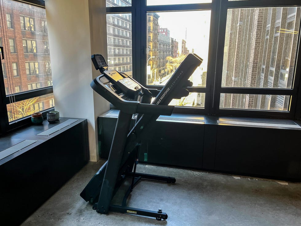 A treadmill positioned next to a large window in an urban setting