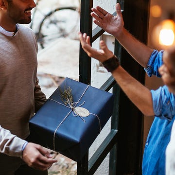 man holding gift walking into front door