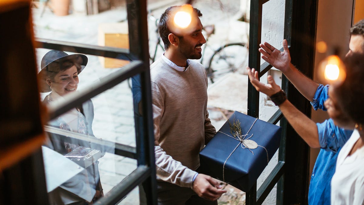 man holding gift walking into front door