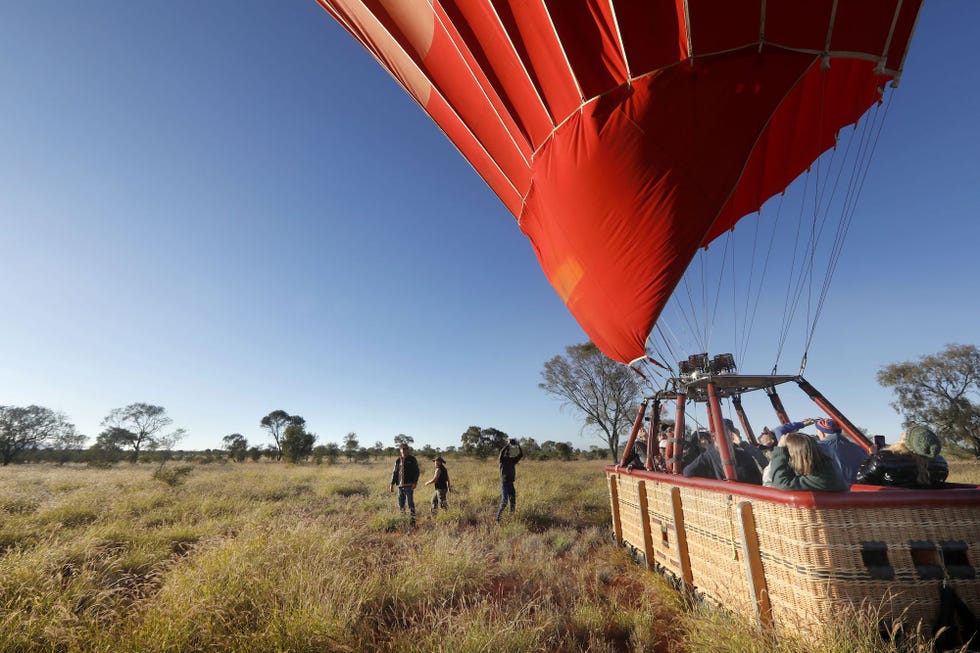a group of people walking under a red and white hot air balloon