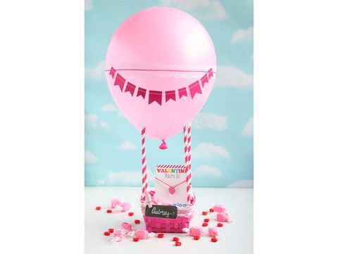 pink hot air balloon valentine box made from basket, striped paper straws, and pink balloon festooned with pennant banner