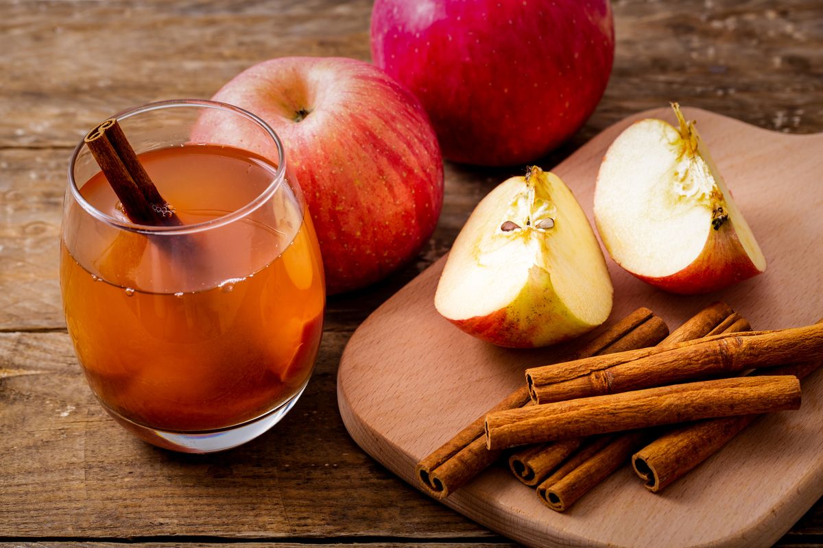hot apple cider with cinnamon stick on wooden background, healthy lifestyle