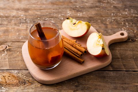 hot apple cider with cinnamon stick on wooden background, healthy lifestyle