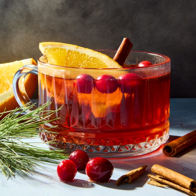 hot cocktail in a glass mug topped with cranberries and lemon