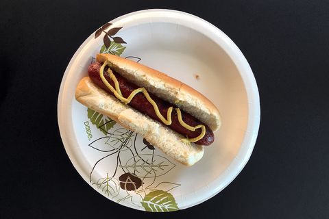 hot dog with mustard and bun on paper plate