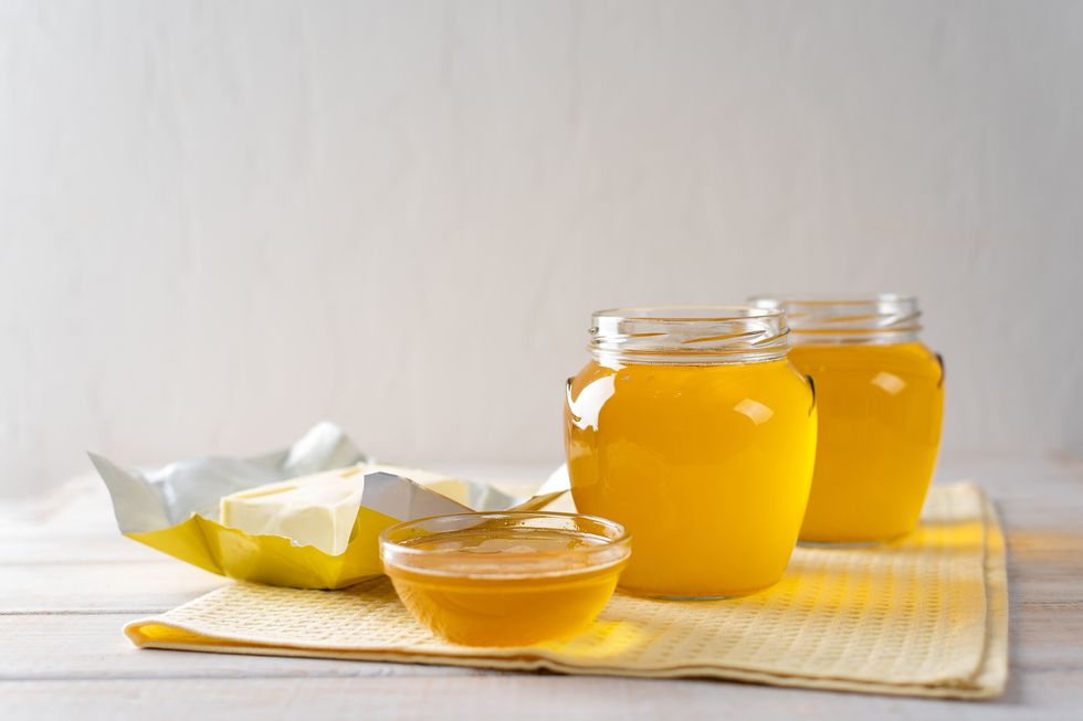 Hot homemade ghee butter in glass jars on a light background.