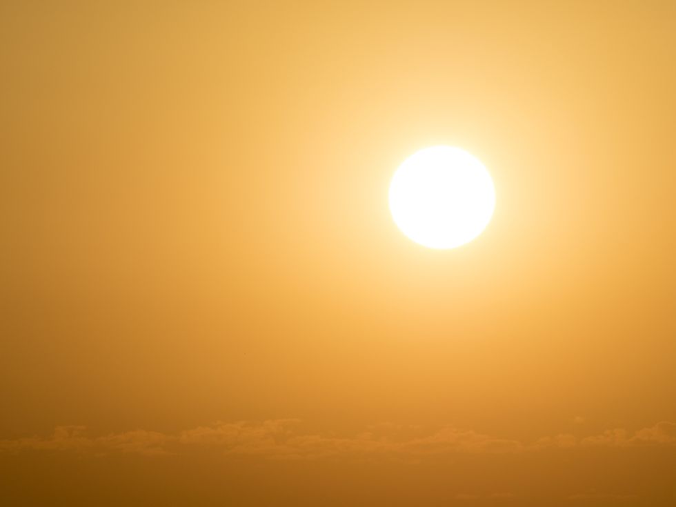 full frame glowing sun at sunset with an orange and yellow sky