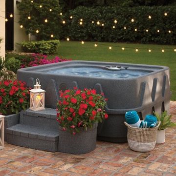 hot tub in backyard with string lights lantern potted flowers