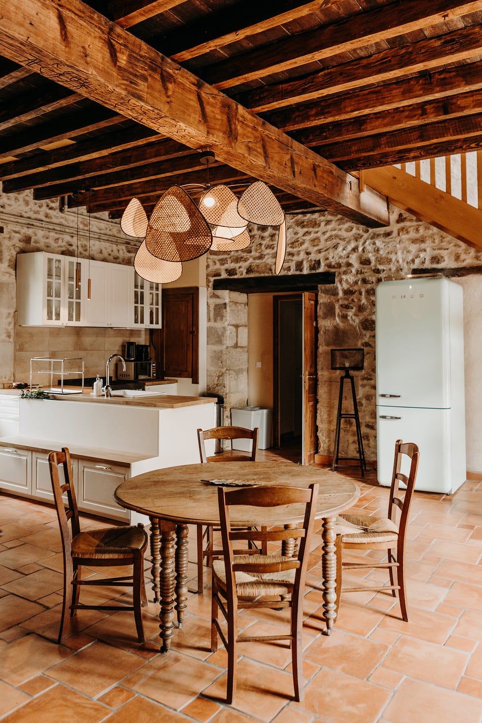 salón comedor rústico con cocina abierta y paredes de piedra y muebles de madera antiguos