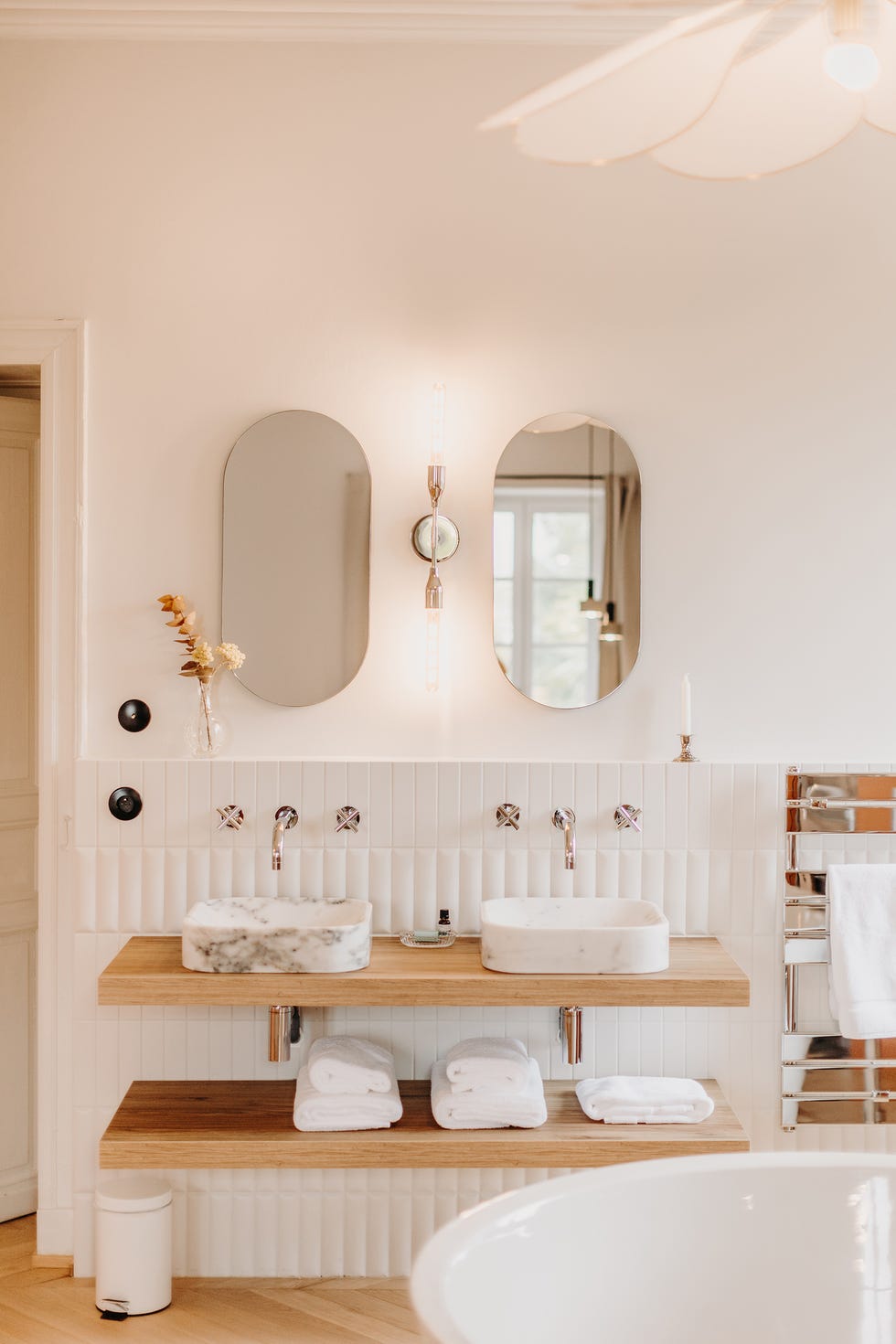 baño con azulejos blancos y encimera de madera con dos lavabos de mármol