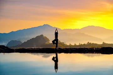 woman practicing stretching on the high mountain slopes in the morning mist and by the reflection ponds