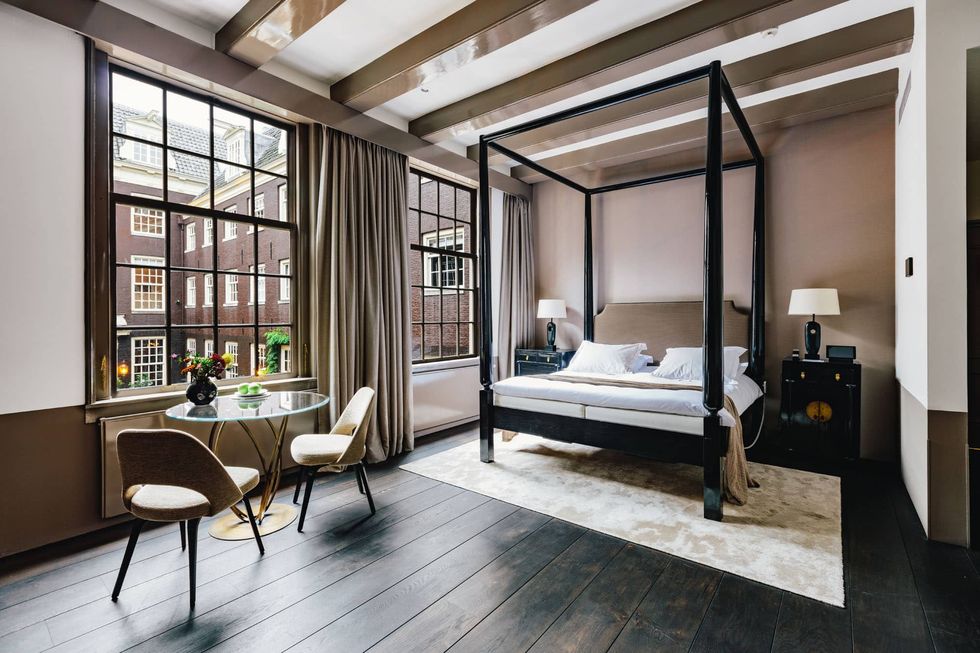 a bedroom with a four poster bed and chairs