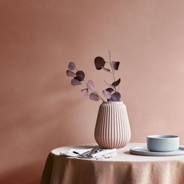 walls painted in pink, with vase and plates on round table