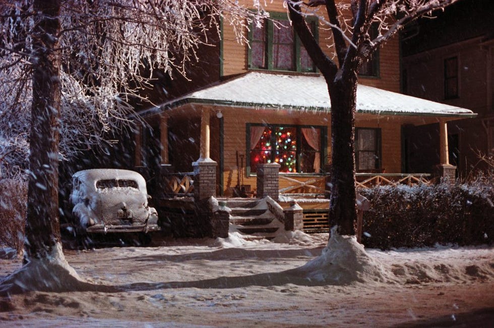 snowy winter scene featuring a house decorated for the holidays