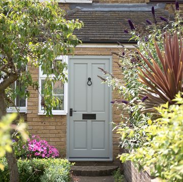 a general exterior view of a sage green front door of a house with a white picket gate of a home