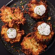 latkes topped with sour cream and chives on a black plate