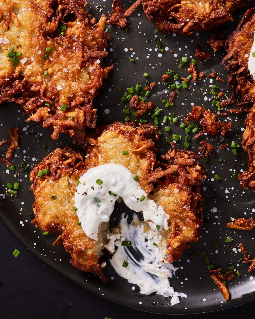 house latkes topped with salt, sour cream, and chives on a black plate