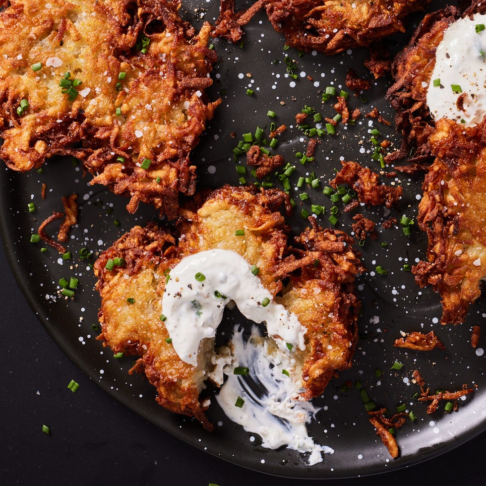 house latkes topped with salt, sour cream, and chives on a black plate