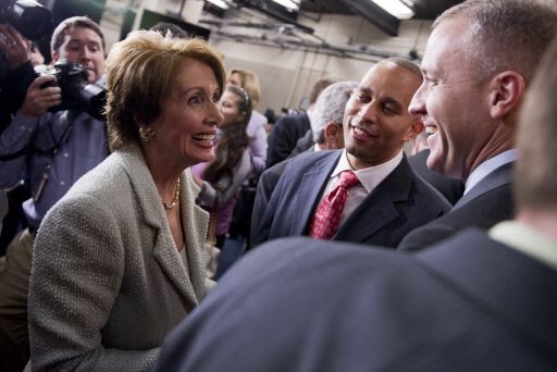 nancy pelosi, hakeem jeffries, and sean patrick maloney smile as they look among one another, they are surrounded by a crowd of people, including photographers
