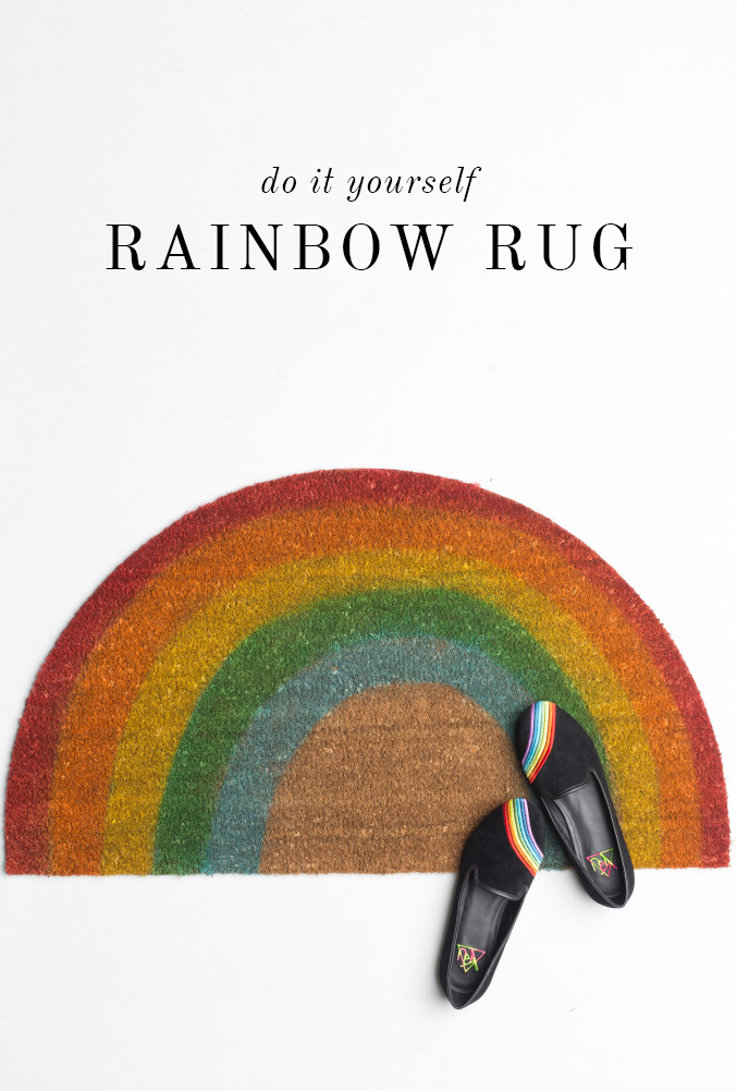 Rainbow striped shoes are placed on a semicircular textile doormat with rainbow stripes on it