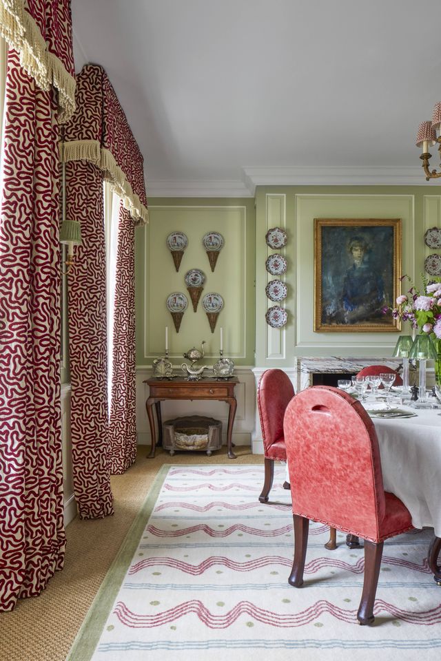 a vibrant varied mix of reds in distressed leather chairs and a painterly rug and velvet on silk draperies animates the dining room