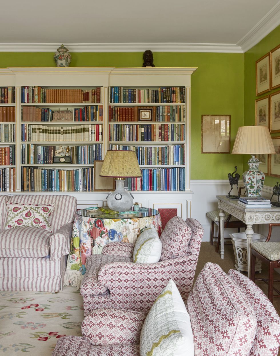 a table skirt made from old colefax and fowler sample books in a drawing room with book shelves and comfy chairs
