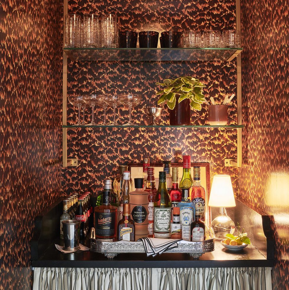 a sexy tortoiseshell wallpaper and antiqued gold shelving dress up an alcove bar for cocktail hour