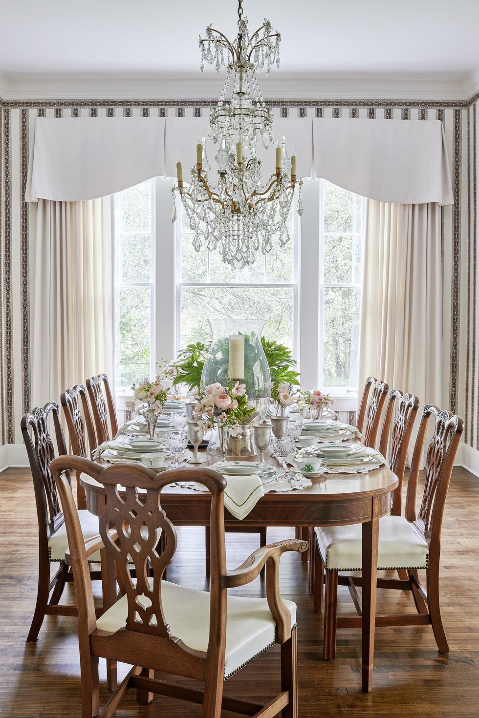the dining room table and leather upholstered chairs are estate pieces, and the crystal chandelier is original to the home