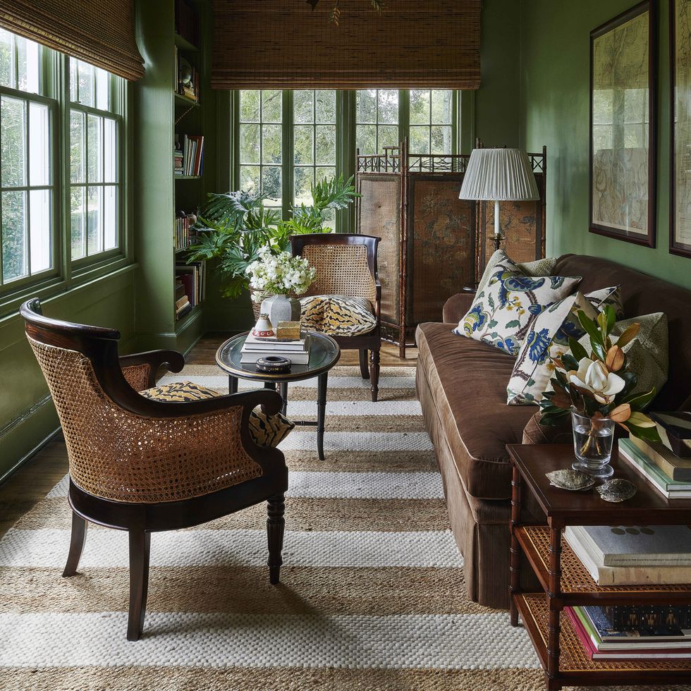 in a family room off the porch a sable brown sofa pairs with caned furniture and a vintage bamboo screen