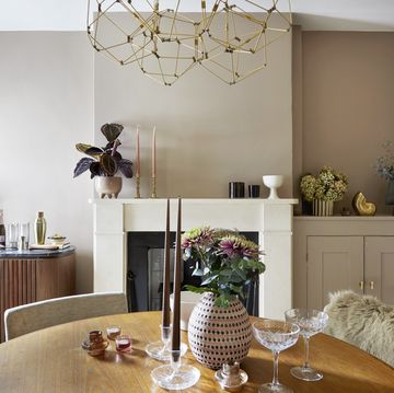 a neutral dining room with gold accessories, round table and fireplace